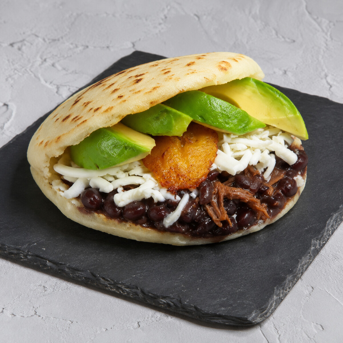 Arepa criolla, caraotas, queso, carne, aguacate y tajadas